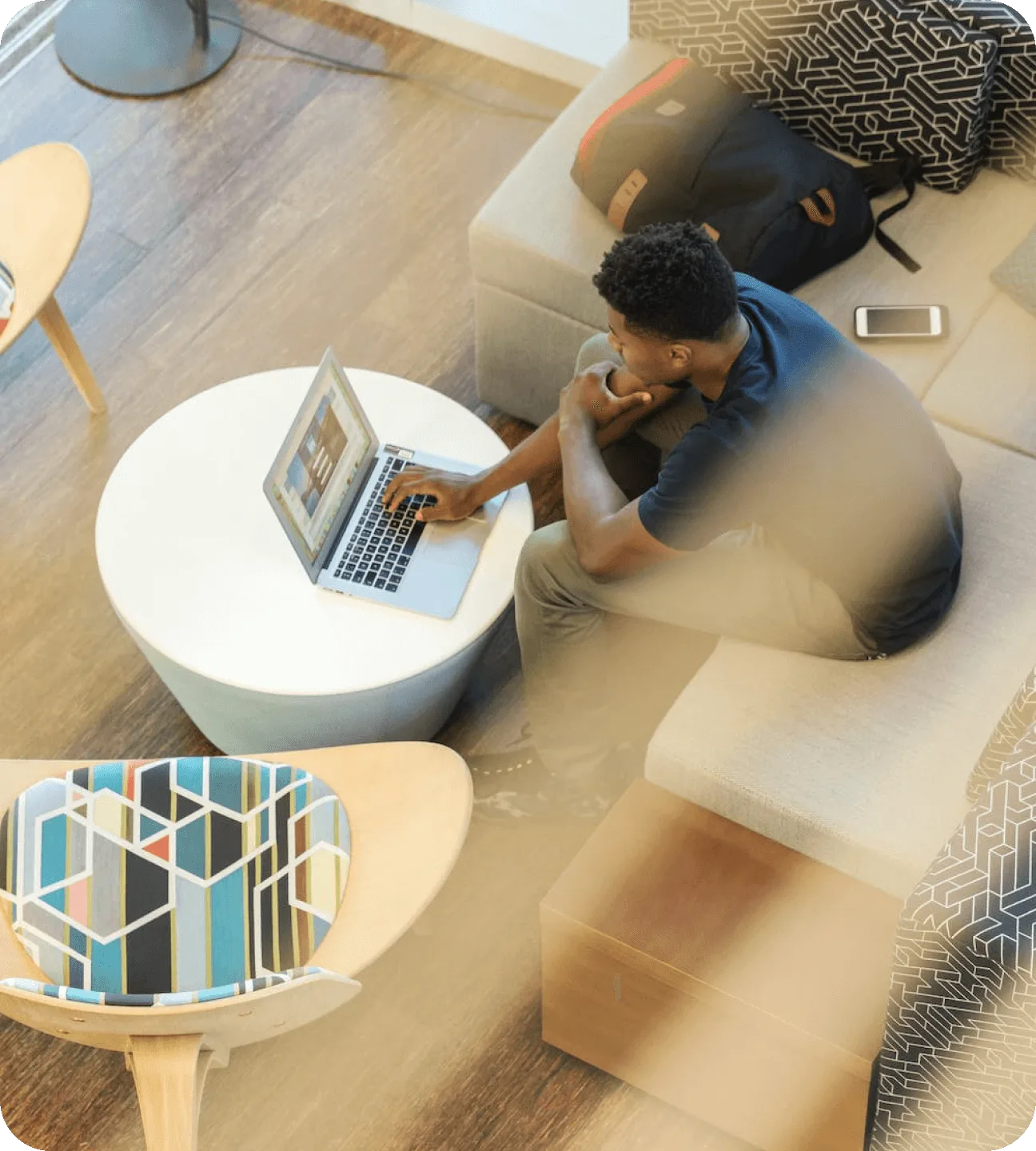 Overhead view of a man working on an open laptop while seated on a sofa in a modern office lounge