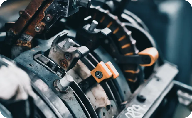 Close-up of greasy steel parts and orange components inside an industrial machine
