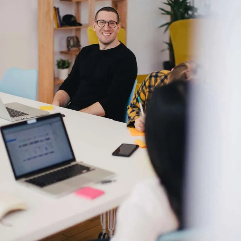 A team member smiling at a desk with an open laptop