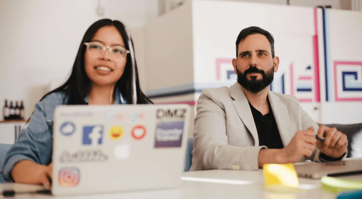 Two colleagues working side by side at a laptop
