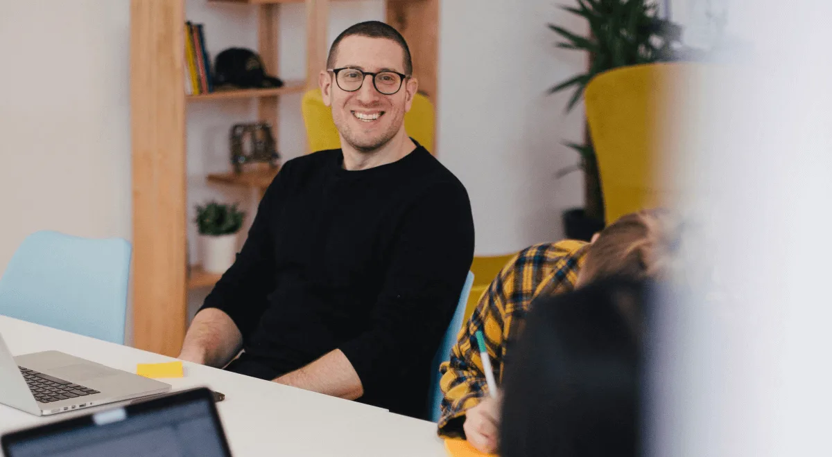 A team member smiling at a white table in a bright office