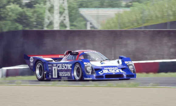 Blue and white Calsonic-liveried Nissan prototype race car, number 1, cornering on a circuit