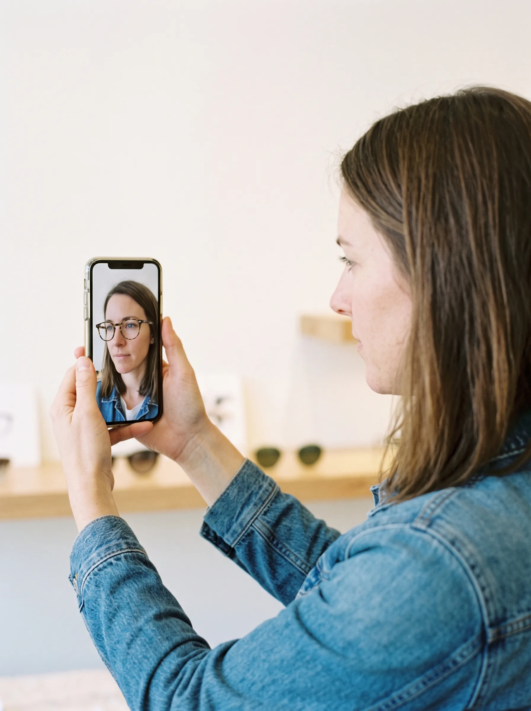 Shopper using virtual try-on to preview eyewear on their own face through a phone camera