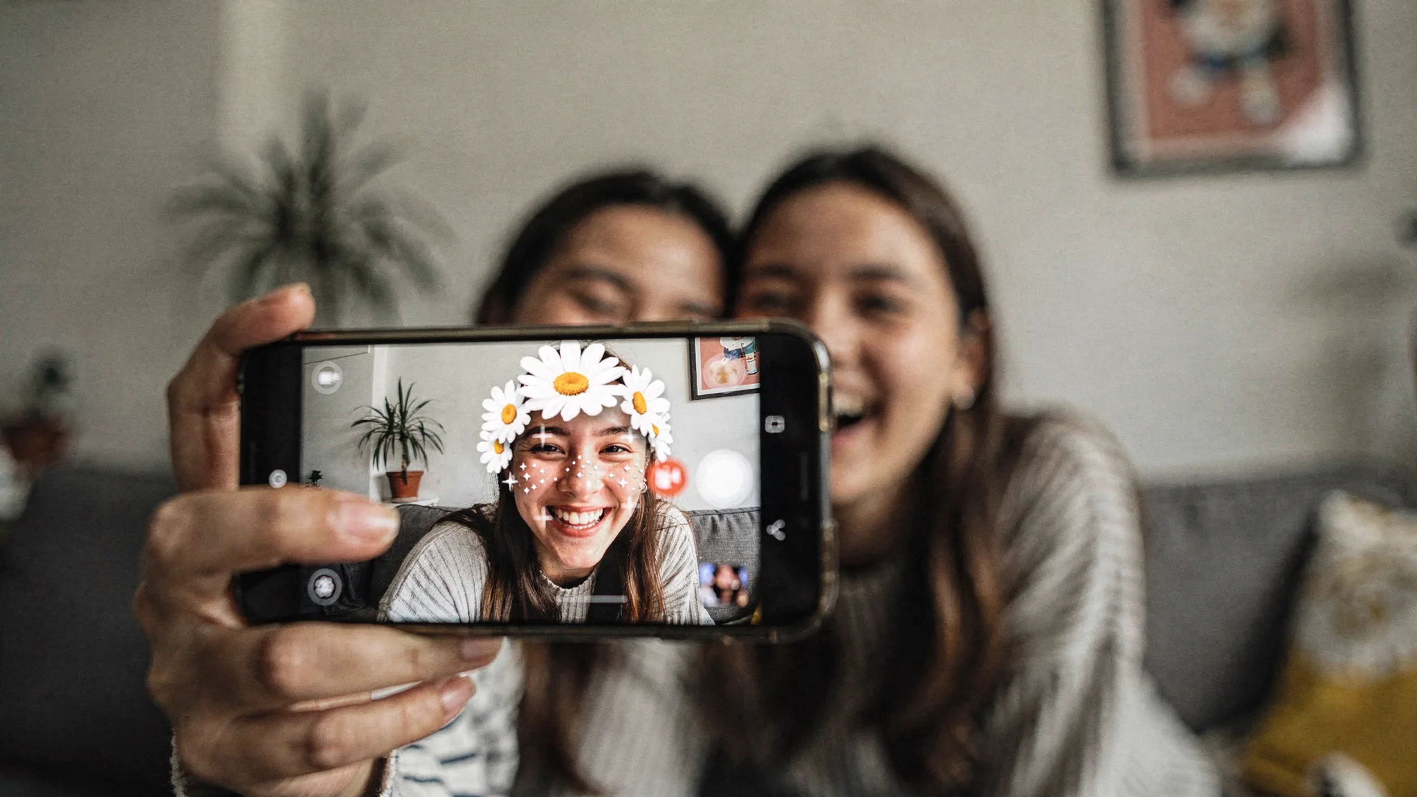 Friends trying a daisy-crown face filter during a social AR selfie