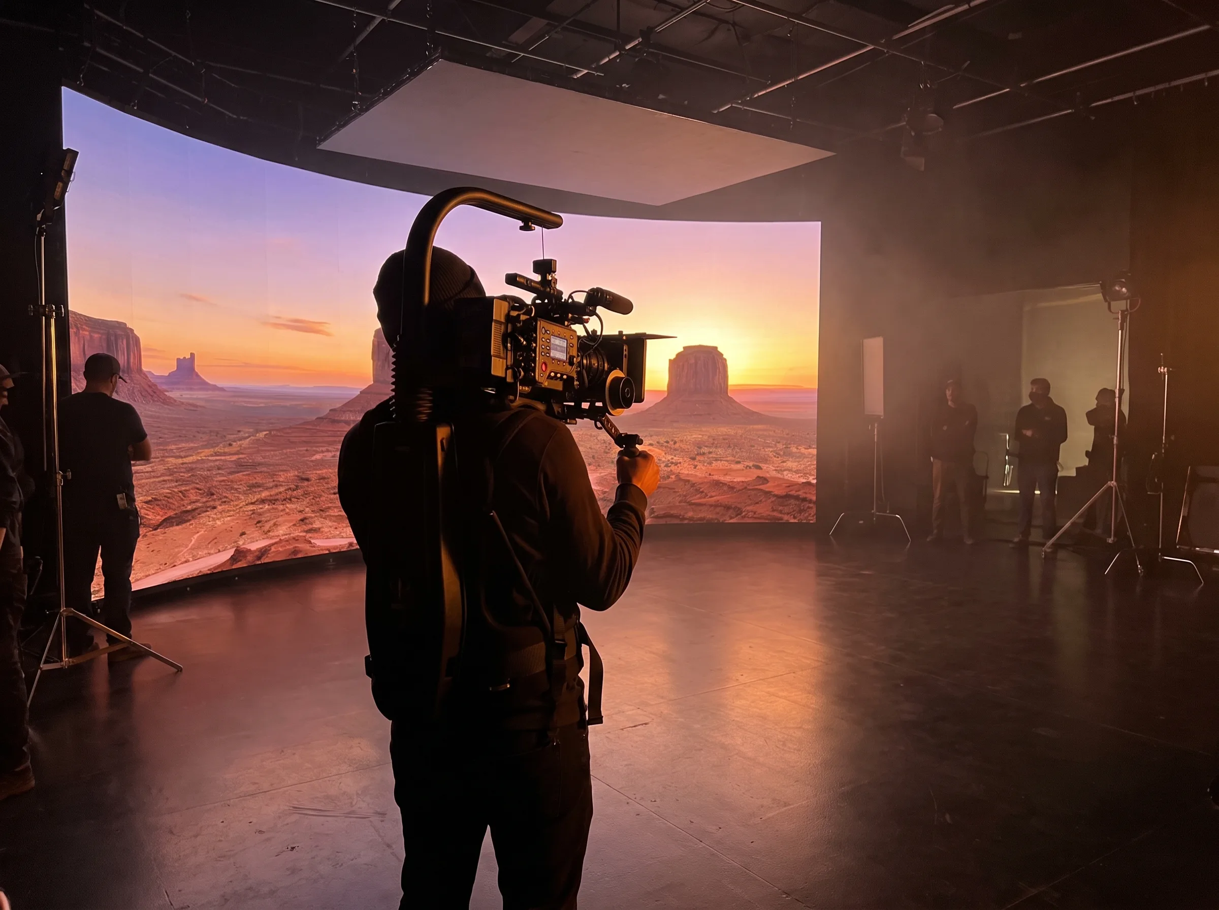 Camera operator filming against an LED volume wall running an Unreal Engine virtual production scene