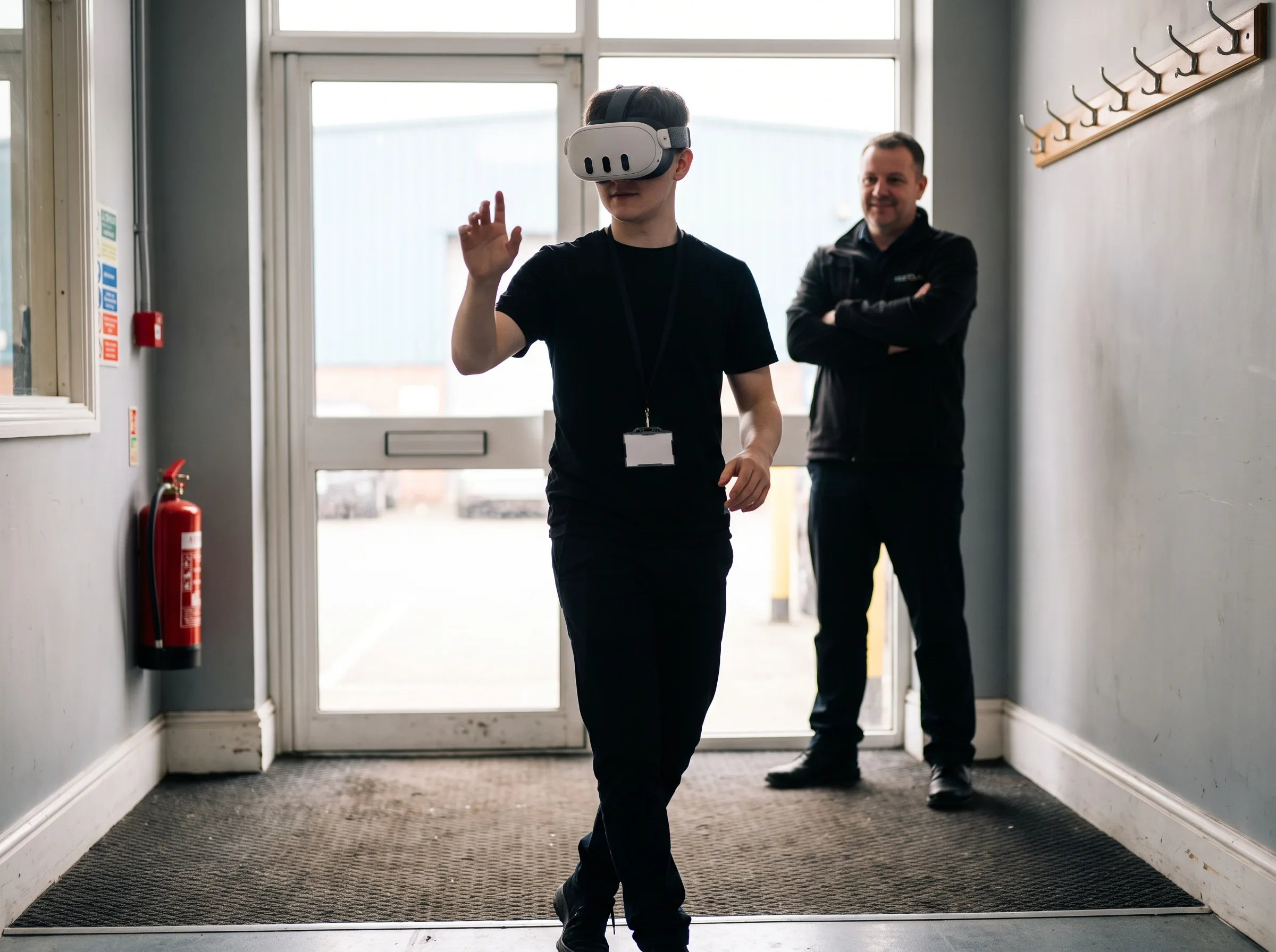 New hire wearing a Meta Quest 3 headset on a VR onboarding facility walkthrough while a supervisor observes