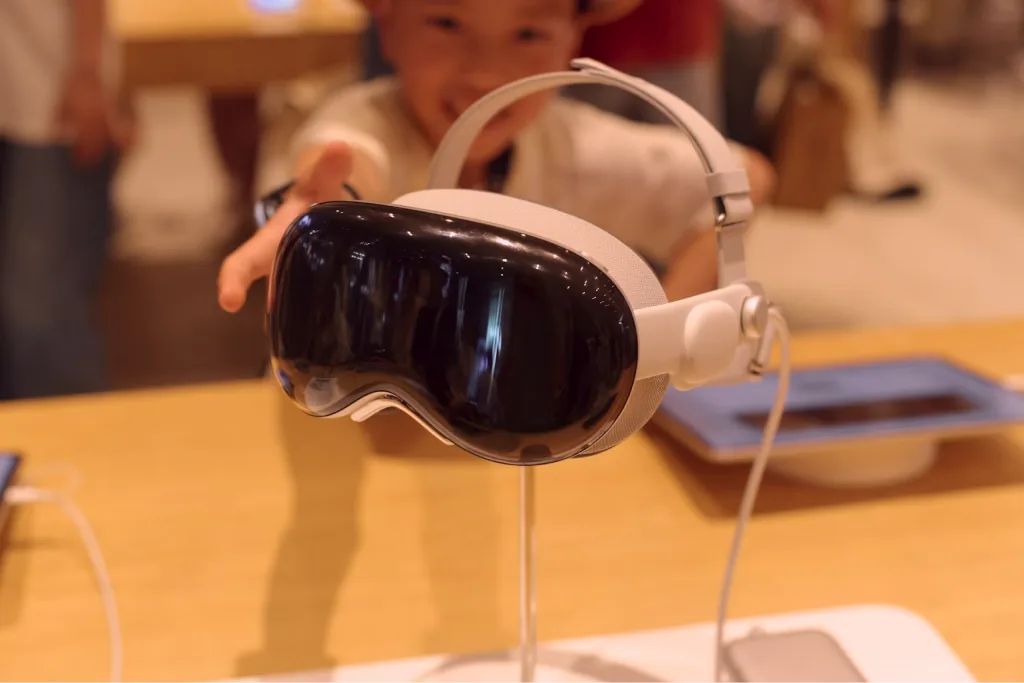 A child reaching for an Apple Vision Pro on a table
