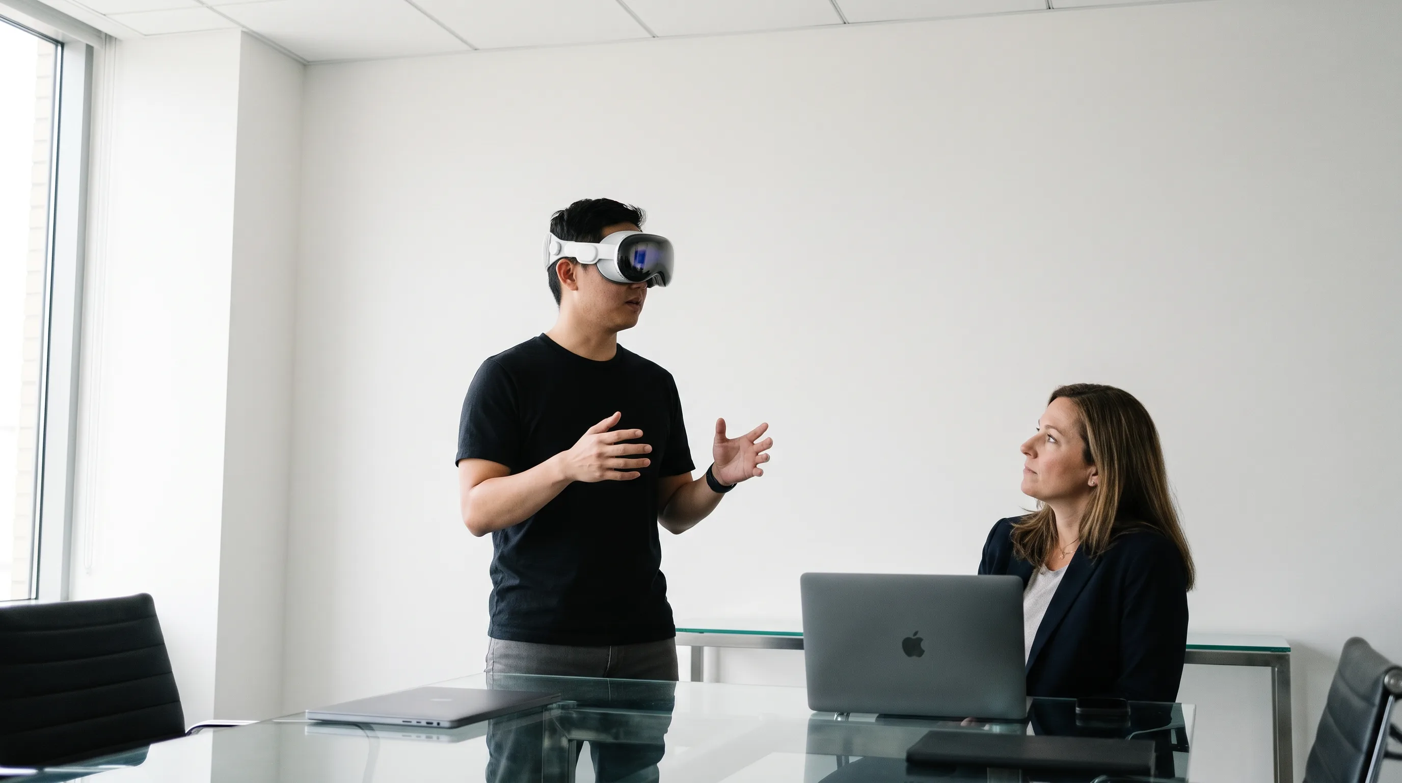 A mixed reality developer wearing Apple Vision Pro demonstrates a spatial app to a business stakeholder in a meeting room