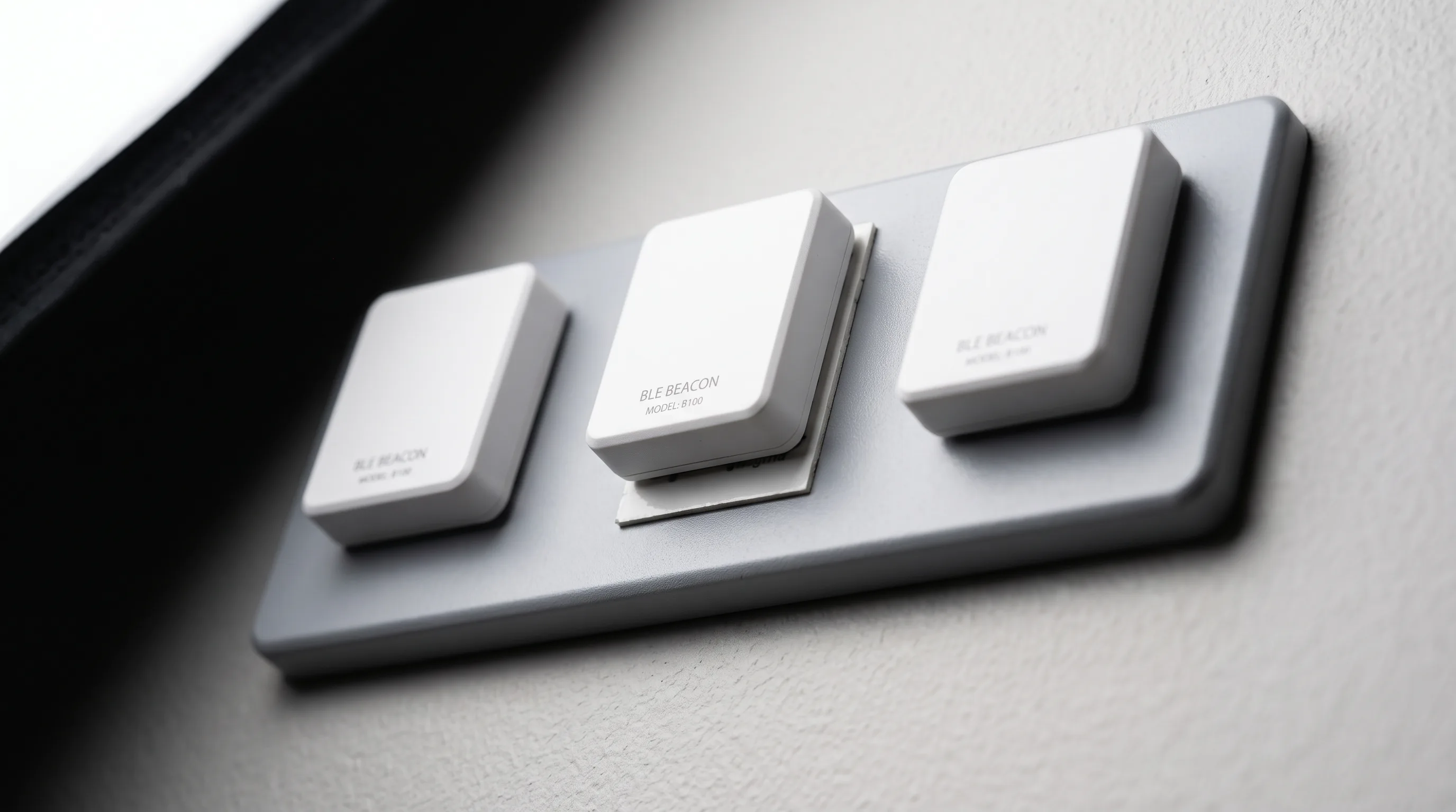 BLE beacon transmitters mounted on a wall bracket in an office corridor