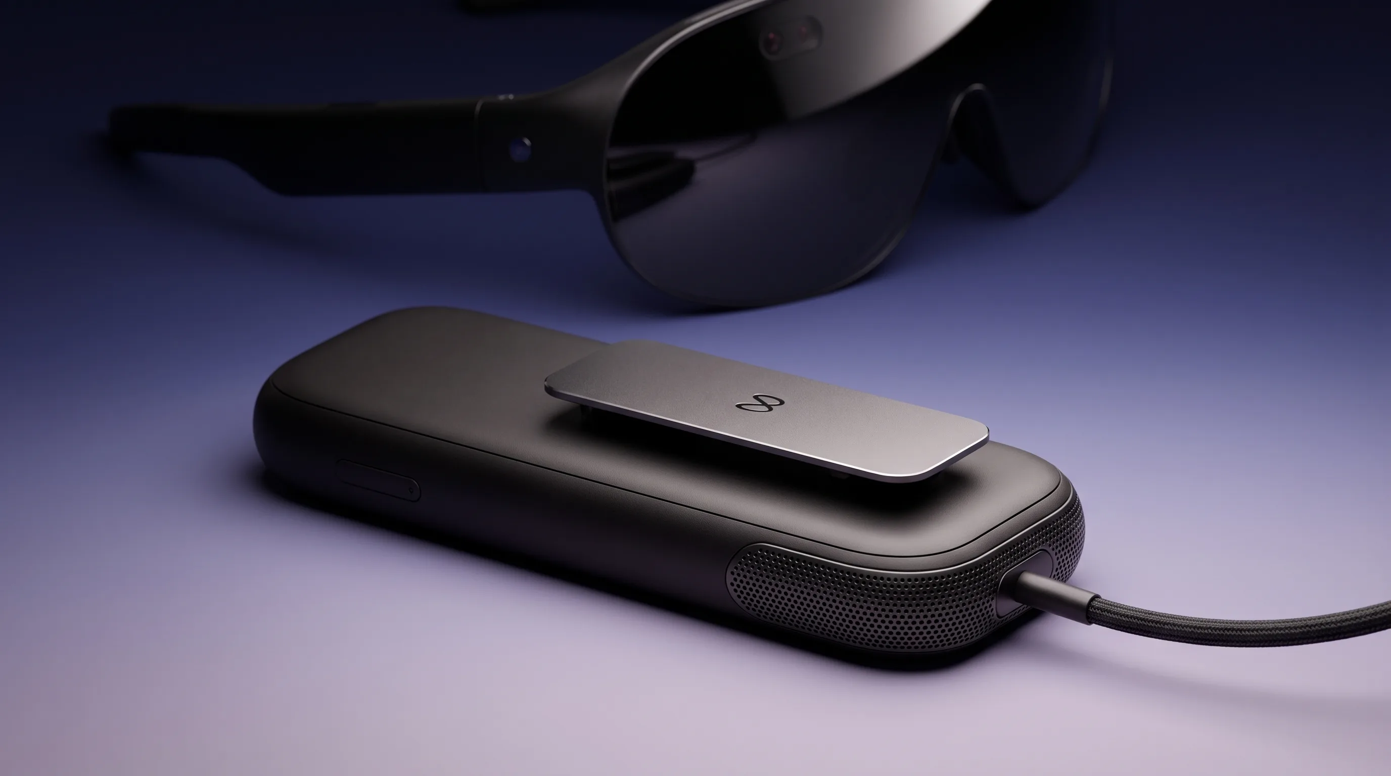 Meta VR Glasses compute puck with its speaker grille and metal clip on an indigo-to-lavender gradient, glasses out of focus behind