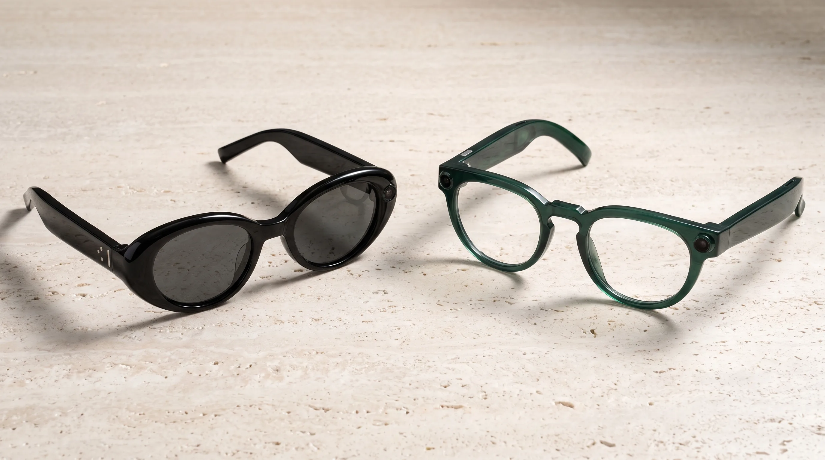 Samsung smart glasses in both launch designs, the black Gentle Monster oval frame and the green Warby Parker round frame, on a stone surface